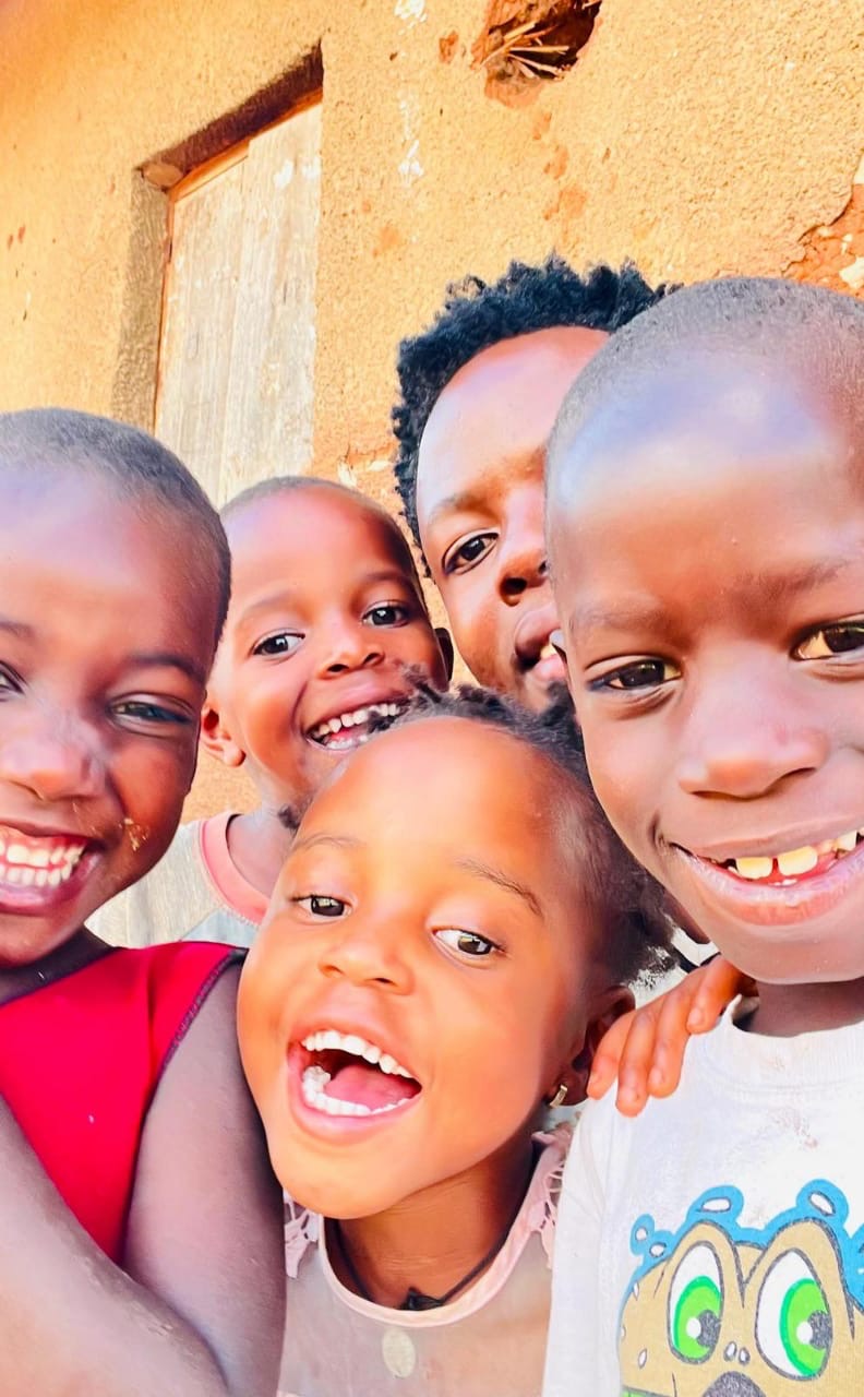 Children of Hope for Mubende laughing outside their home in golden light